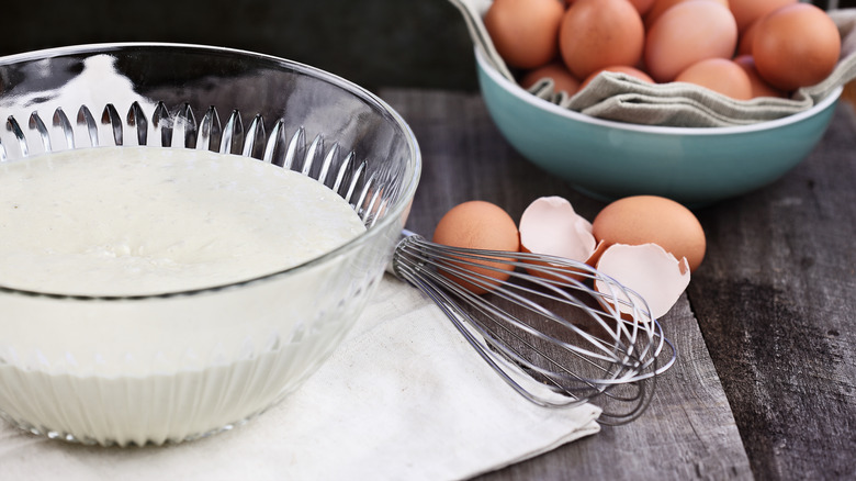 Batter sitting in a bowl next to eggs