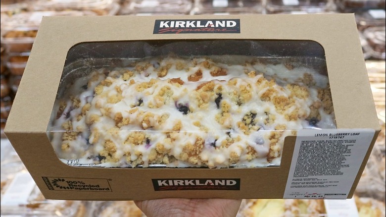 A package of the Lemon Blueberry Loaf held over a display of pastries