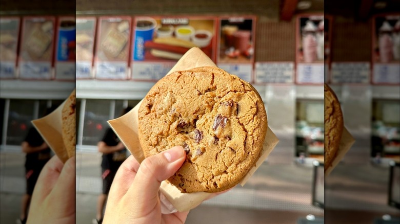 Someone holds up the Chocolate Chunk Cookie from the food court