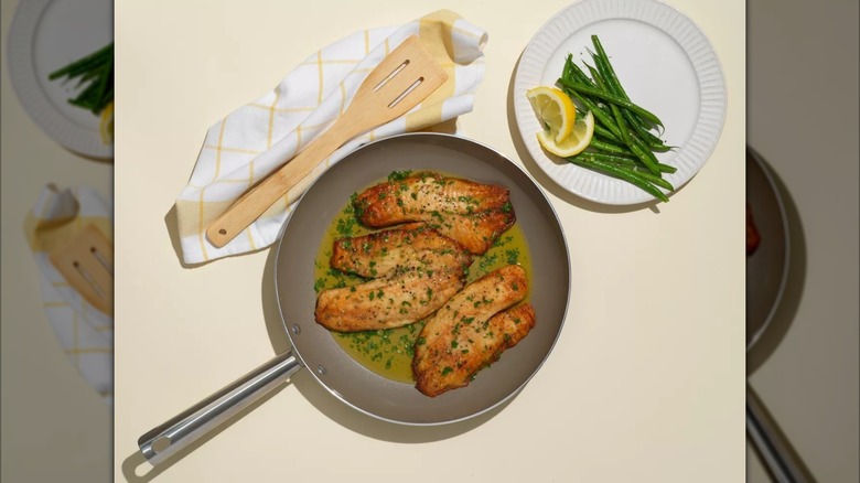three fish filets with butter and parsley sauce in a GoodCook Essentials Ceramic Nonstick Frypan.