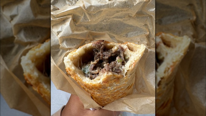 Stuffing of a Costco Jumbo Bulgogi Bake seen in a half eaten sandwich