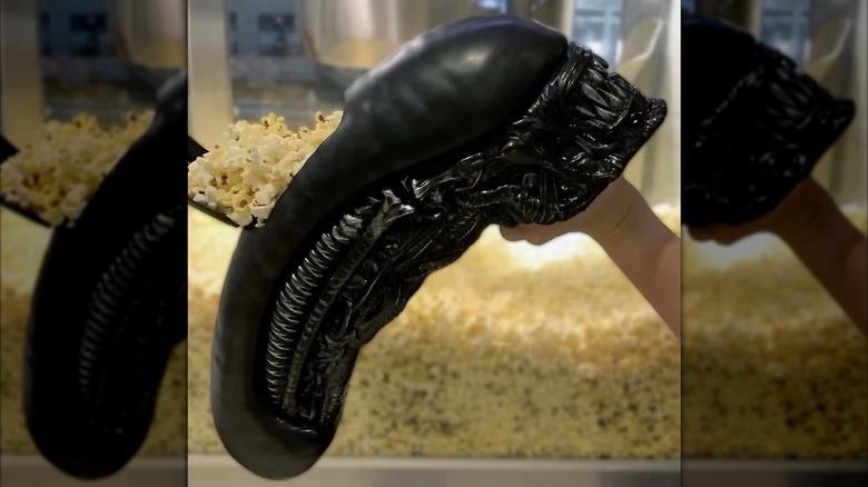 A hand holds up an "Alien: Romulus" popcorn container