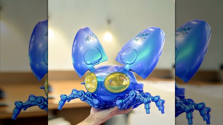 A hand holds up a "Blue Beetle" popcorn container with its wings up