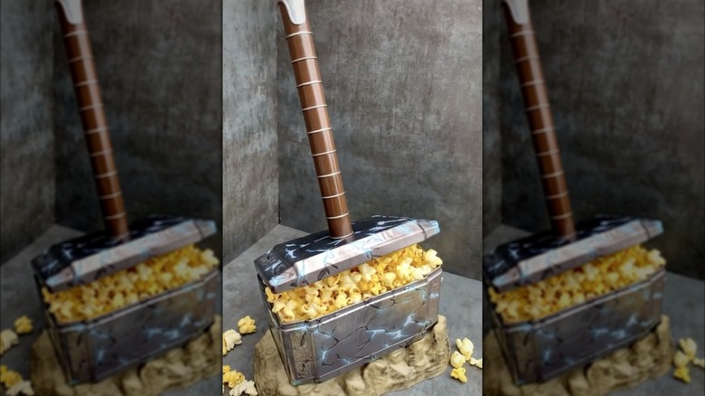 A popcorn holder replica of Thor's hammer, with popcorn spilling out of the hammer head