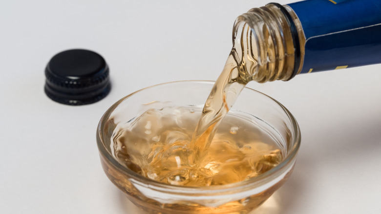 Pouring cooking sherry into small glass bowl