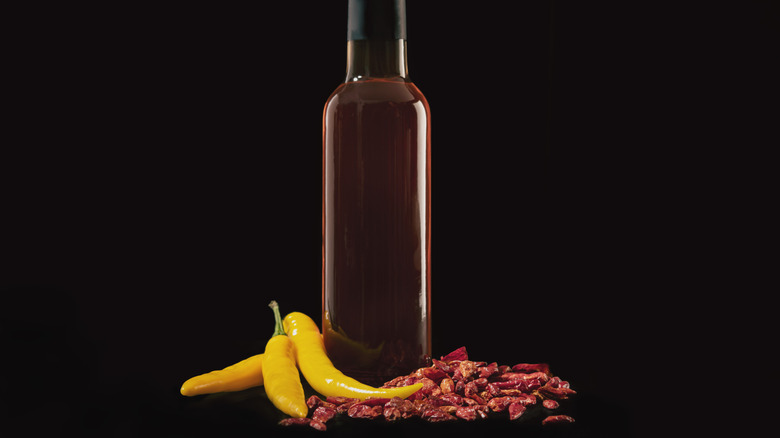 Bottle of hot sauce with fresh and dried spicy peppers