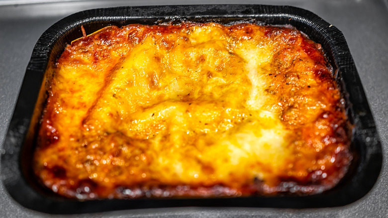 Crispy and melty top of a heated lasagna served in a black tray