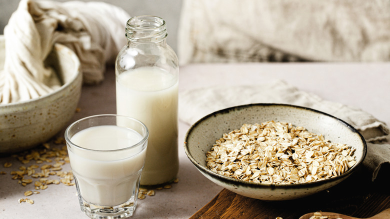Oats in a ceramic bowl alongside a bottle of oat milk