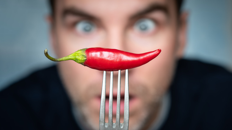 Man holding chili pepper on a fork