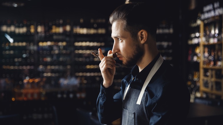 a waiter sniffing a wine cork