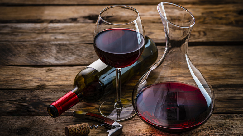 horizontal wine bottle next to a glass and carafe of red wine