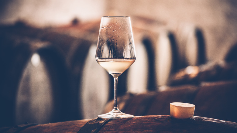 a class of white wine on a barrel