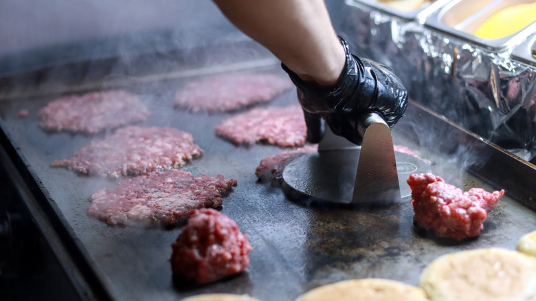 Person making smash burger with burger press