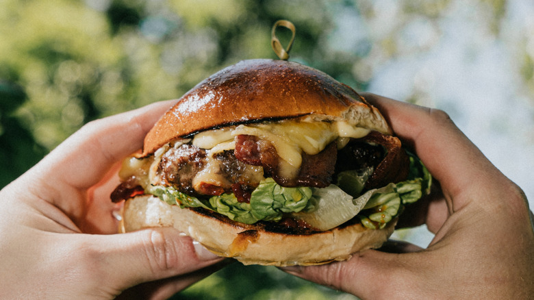 Person holding cheeseburger in the air