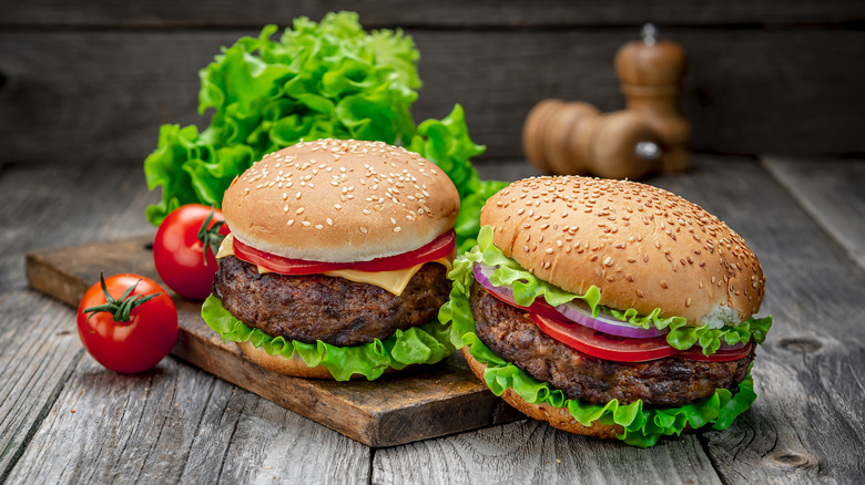 two cheeseburgers on wooden board