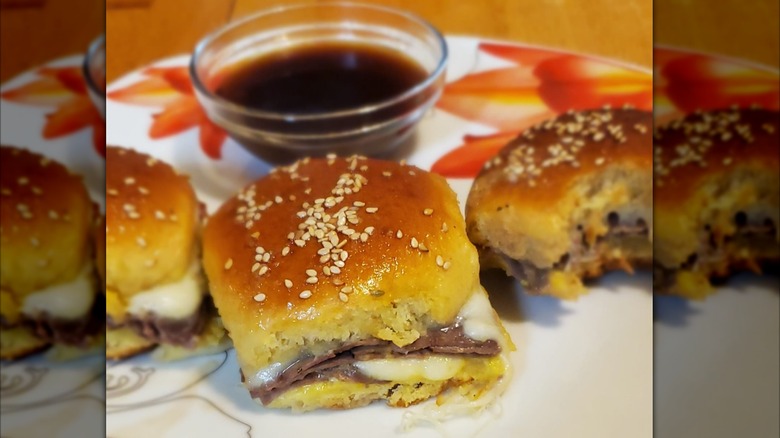 Au jus sliders sit on a plate.