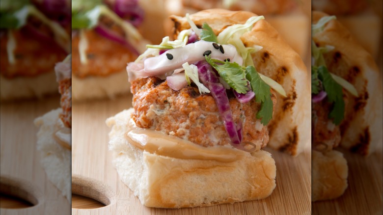 A salmon slider sits on a cutting board.