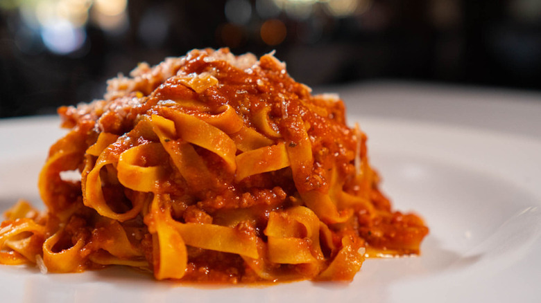 close up of fettuccini bolognese pasta on a white plate