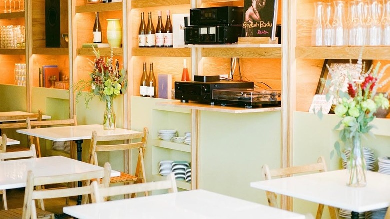 interior of a bright los angeles restaurant with several small tables and shelves lining the walls