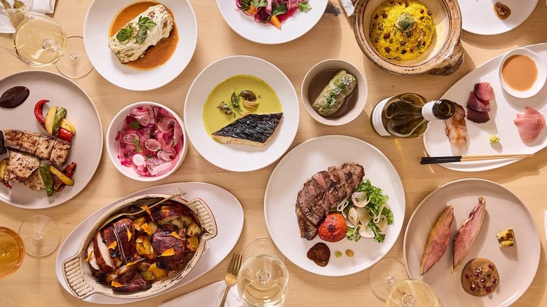 top down shot of a table full of several dishes of food, glasses of wine, and a wine bottle