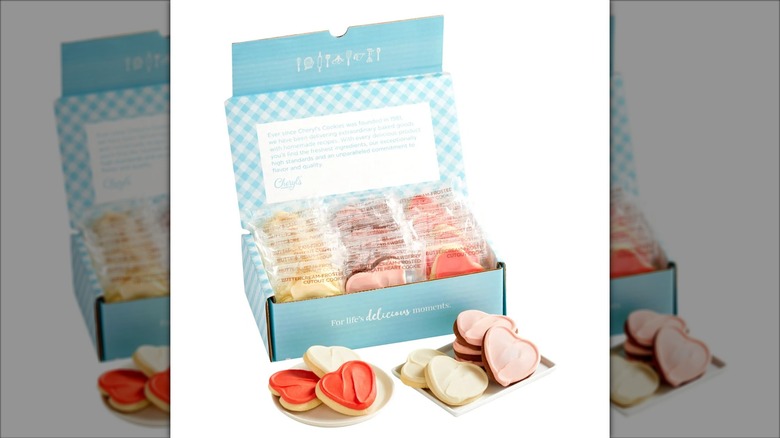 An open box of Cheryl's Cookies with small plates of the cookies sitting adjacent