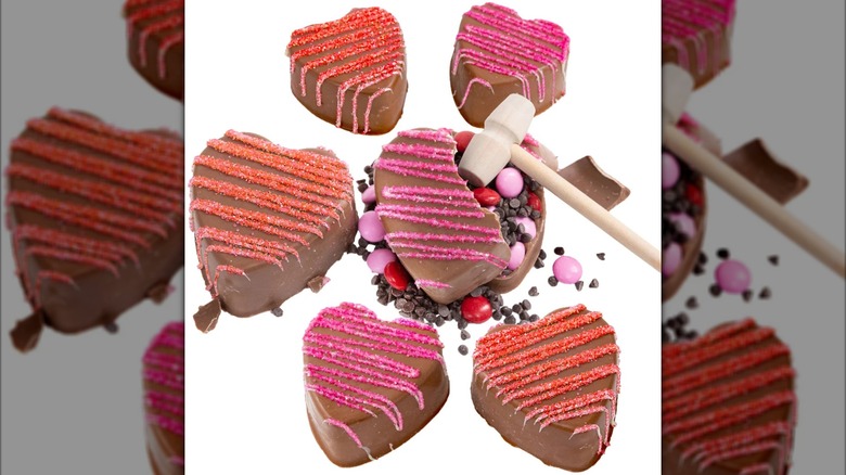 Belgian Chocolate Breakable Hearts, with one broken open, a wooden mallet resting on it, and the chocolate contents spilling out