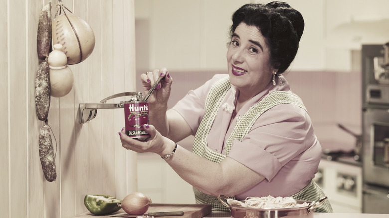 Vintage photo of a person opening a can with a wall-mounted can opener