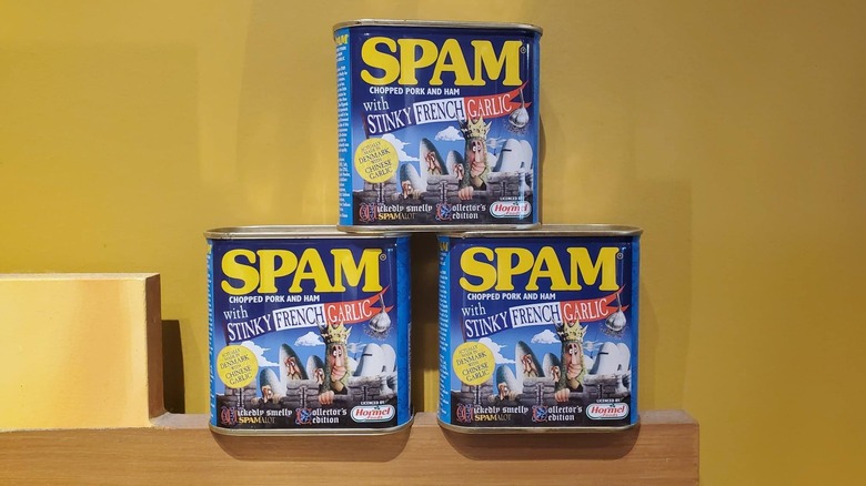 Three cans of Stinky French Garlic SPAM are stacked in a pyramid formation