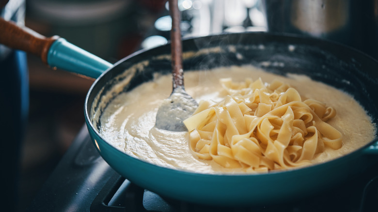 Stirring noodles into alfredo sauce