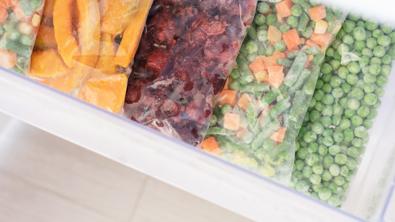 Frozen peas and an assortment of other vegetables in a freezer drawer