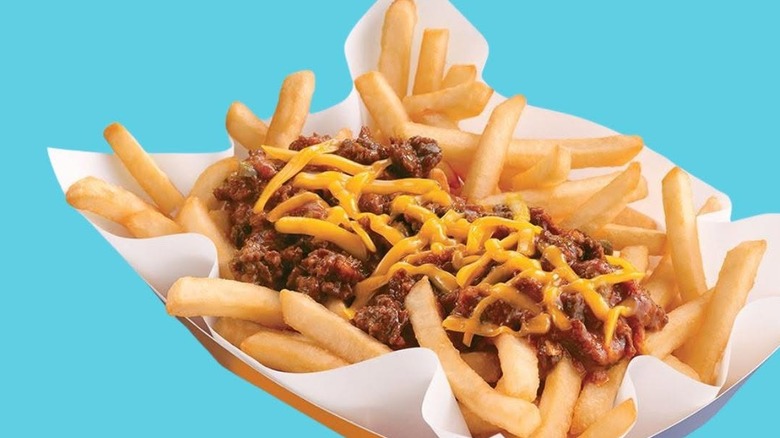 A container of DQ Chili Cheese Fries against a turquoise-blue background