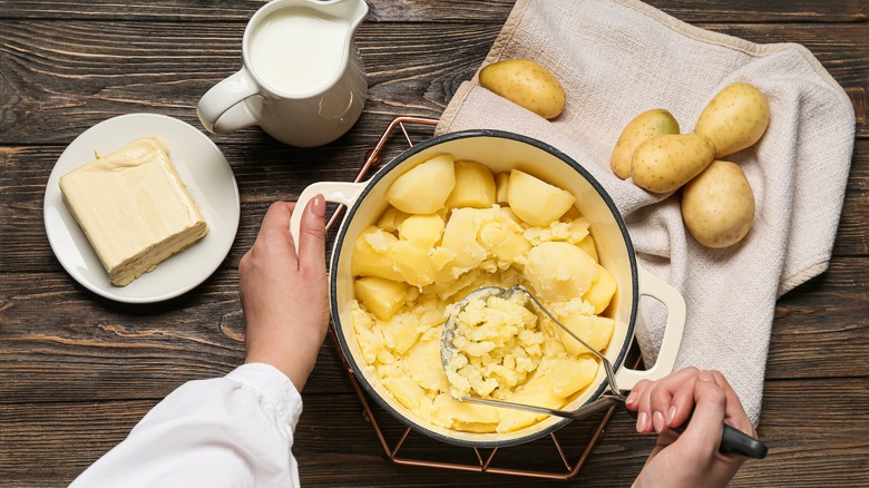 cook's hands preparing mashed potatoes