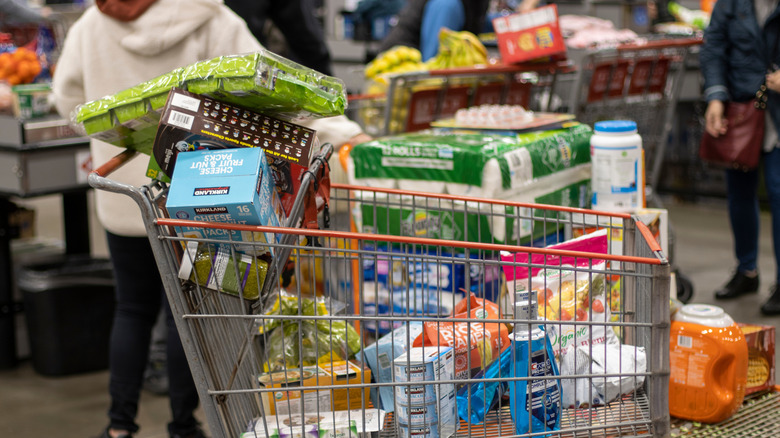 Grocery cart full of Costco foods in busy checkout aisle