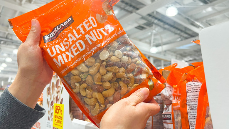 Hands grabbing bag of Kirkland Signature Unsalted Mixed Nuts