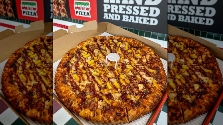 A Jet's Pizza Aloha BBQ Chicken pizza in its box inside a restaurant.