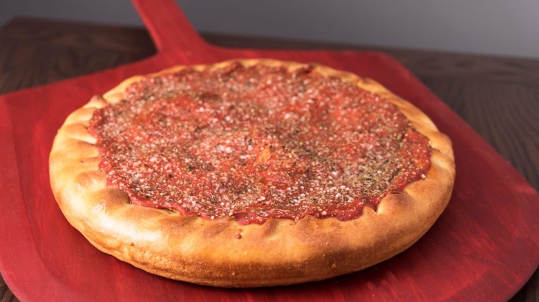 A stuffed pizza from Rosati's Pizza sits on a red pizza peel.