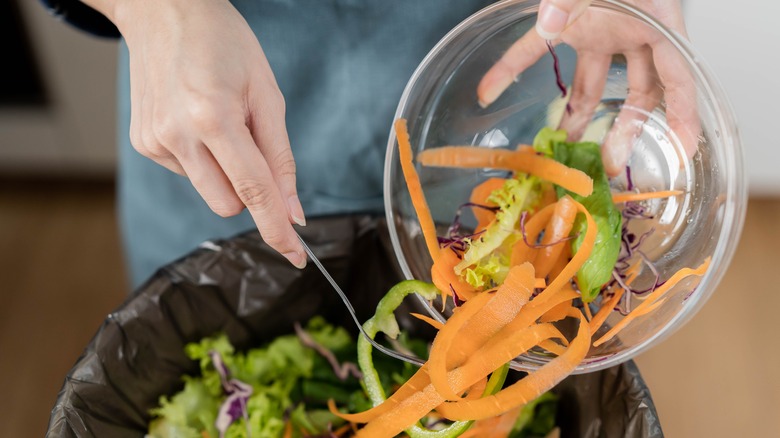 woman adding food scraps to trash