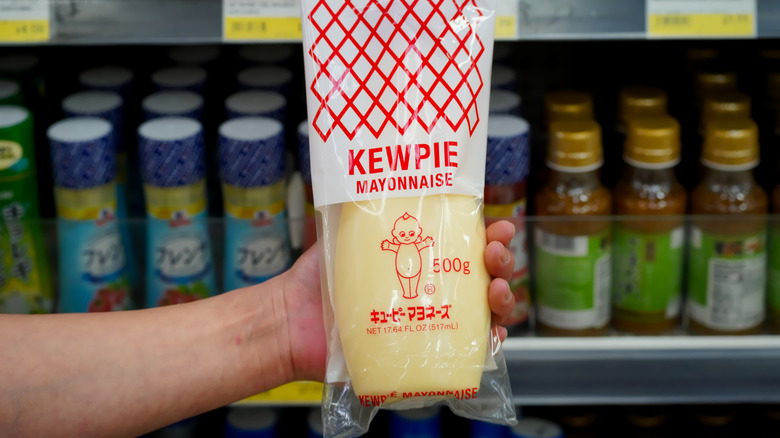 A hand holding a bottle of Kewpie mayo