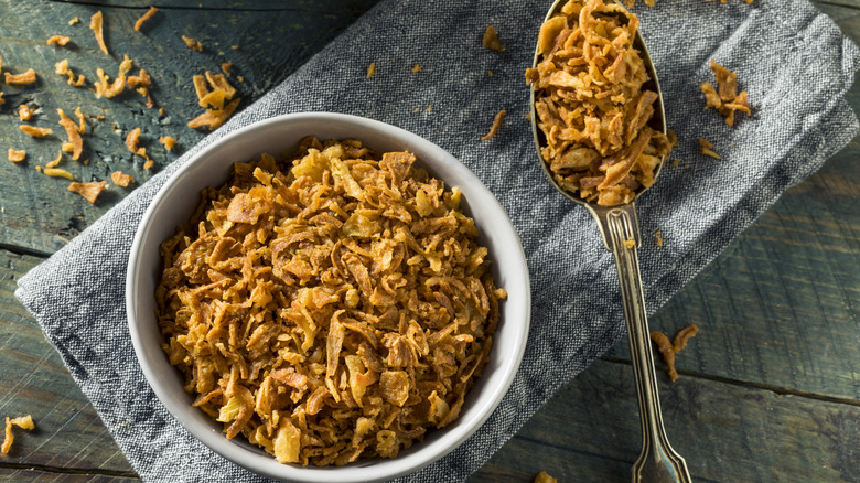 A bowl of fried onions with a spoon next to it