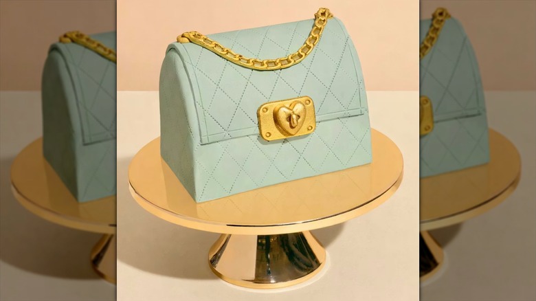 The Sugar Mamma "Mint Condition" Handbag Cake from Charm City Cakes sits on a gold cake stand.
