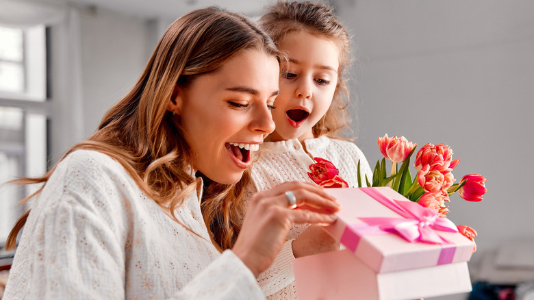 An excited child watches a mother open a gift