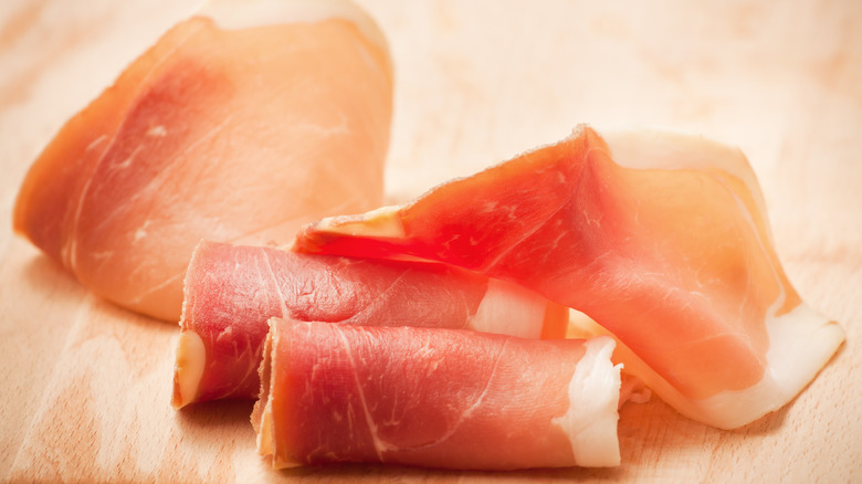 Slices of prosciutto on a wooden cutting board