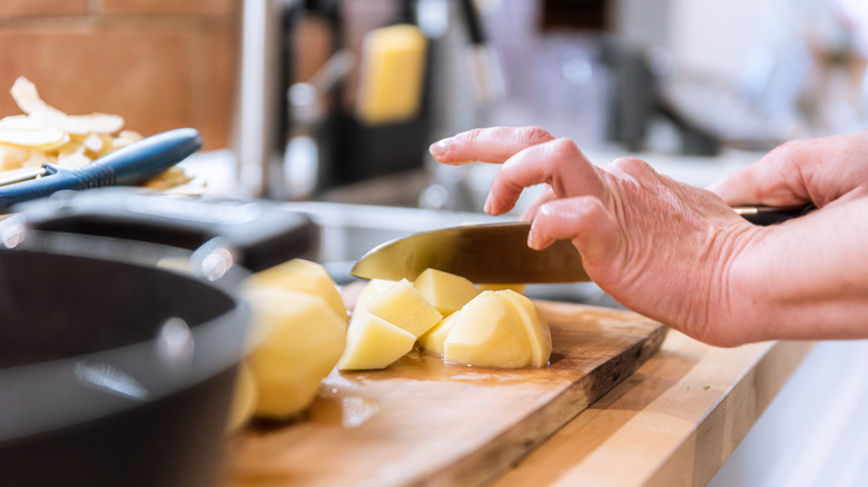 woman chopping potatoes on board