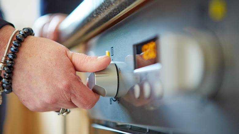 woman turning oven dial