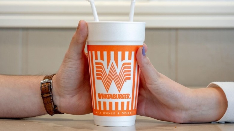 Two hands sharing milkshake from Whataburger