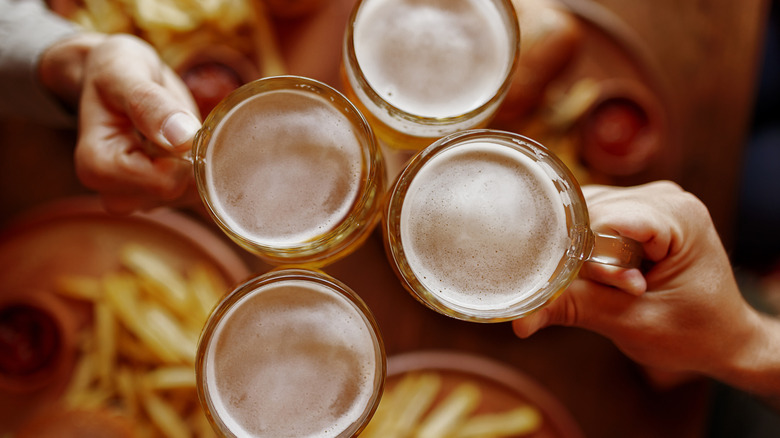 Overhead view of hands toasting beer glasses
