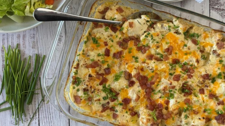 Casserole in a dish on wodden table with chives and bacon