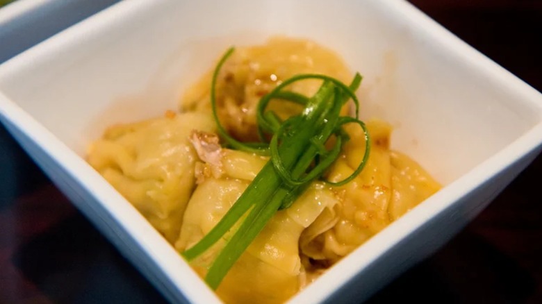 Dumplings in white bowl topped with scallions
