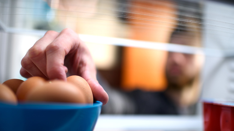 person taking egg from fridge