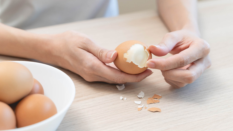 hands slowly peeling hard-boiled egg